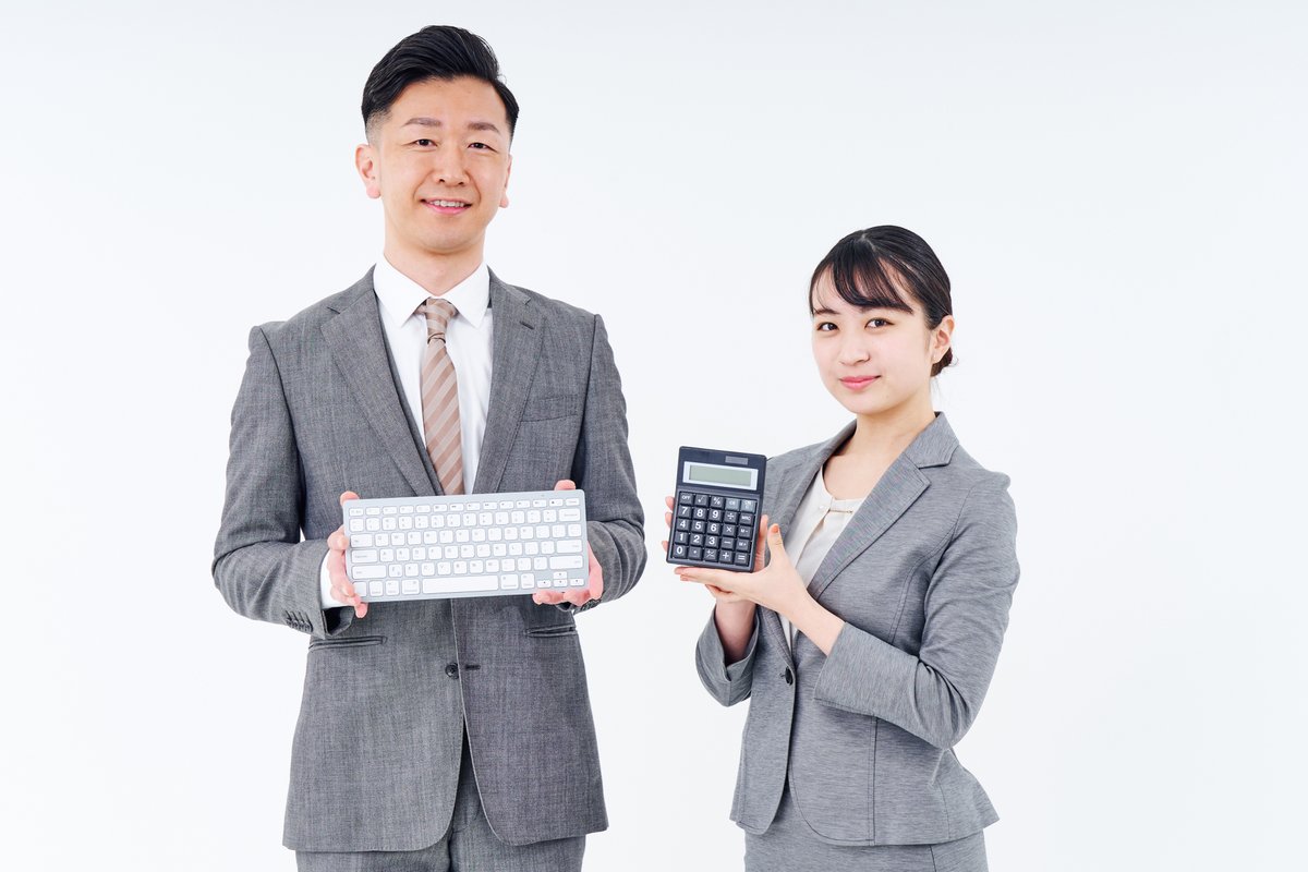 キーボードと計算機を持つスーツ姿の男女