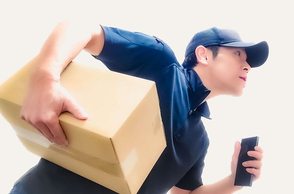 ダンボールとスマホを持って走る男の配達員