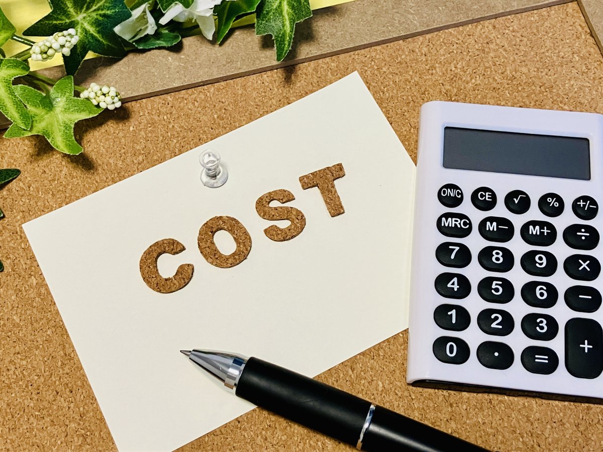 メモに書かれたCOSTの文字と電卓とペン