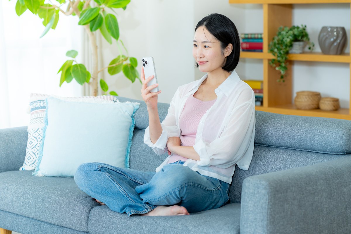 部屋でスマホを操作する女性